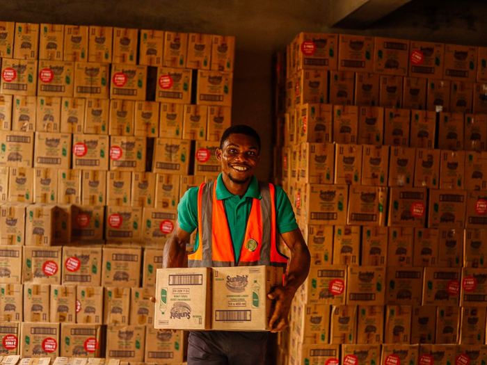 Trabajador de almacén sonriendo mientras carga una caja